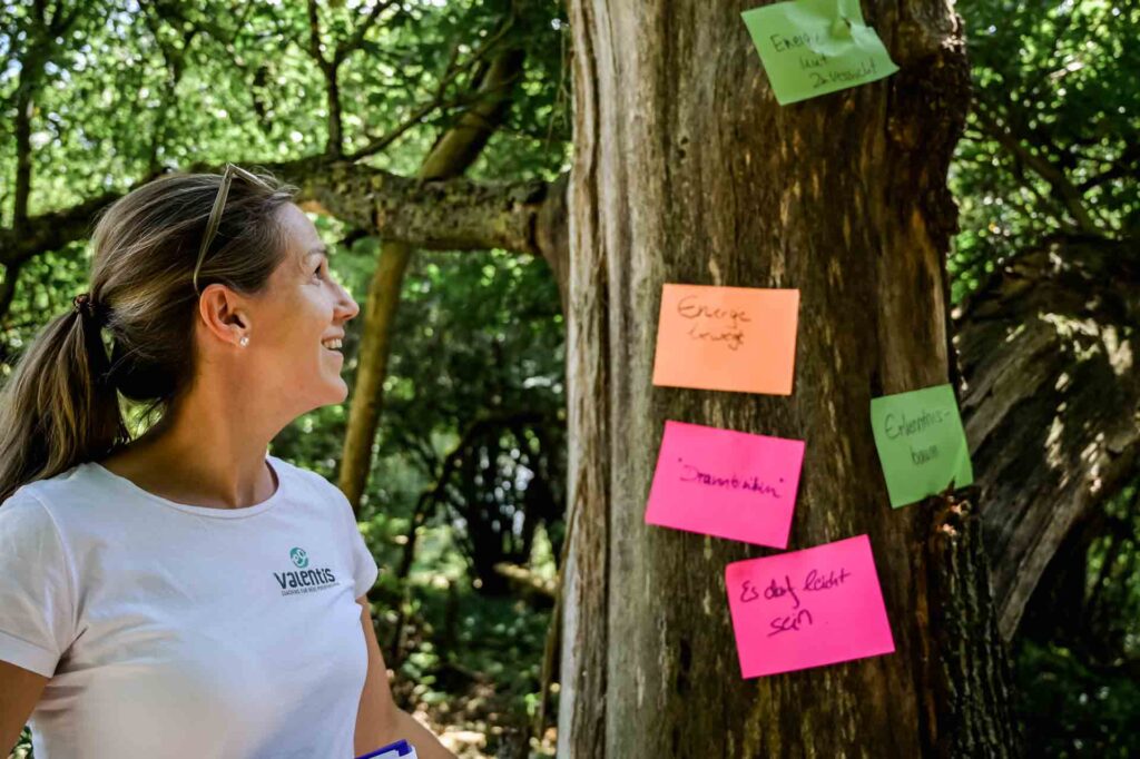 Martina Kammerlander-Fischer neben einem Baum, an den bunte Zettel geheftet worden sind